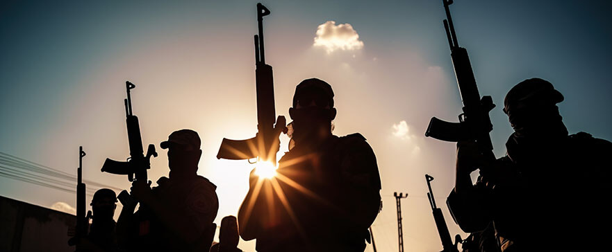 Silhouette of men in camoflage clothing holding automatic rifles